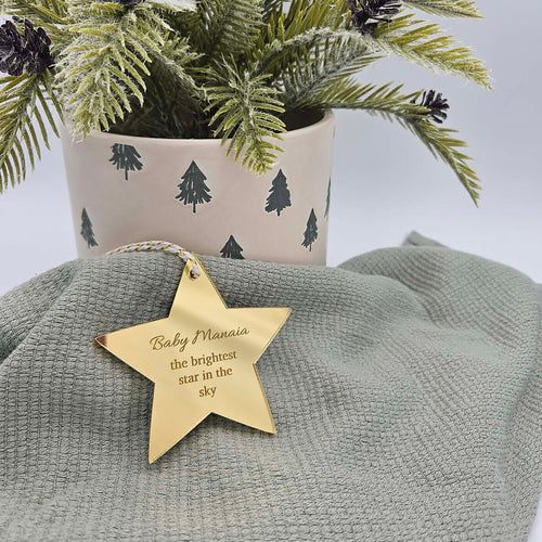 Decorative star tag with engraved message on a green fabric background with a potted plant.