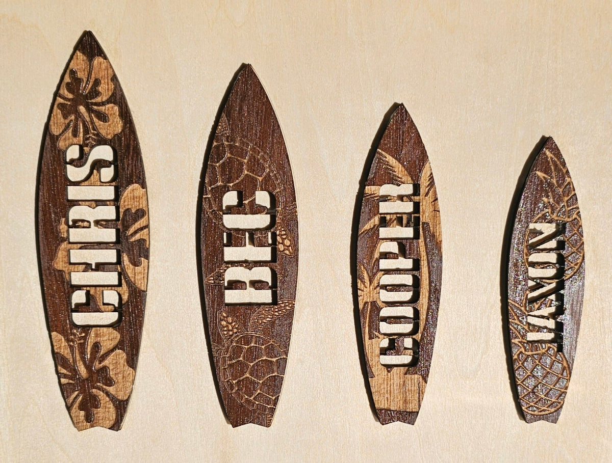 Four wooden surfboard decks with engraved names on a beige background