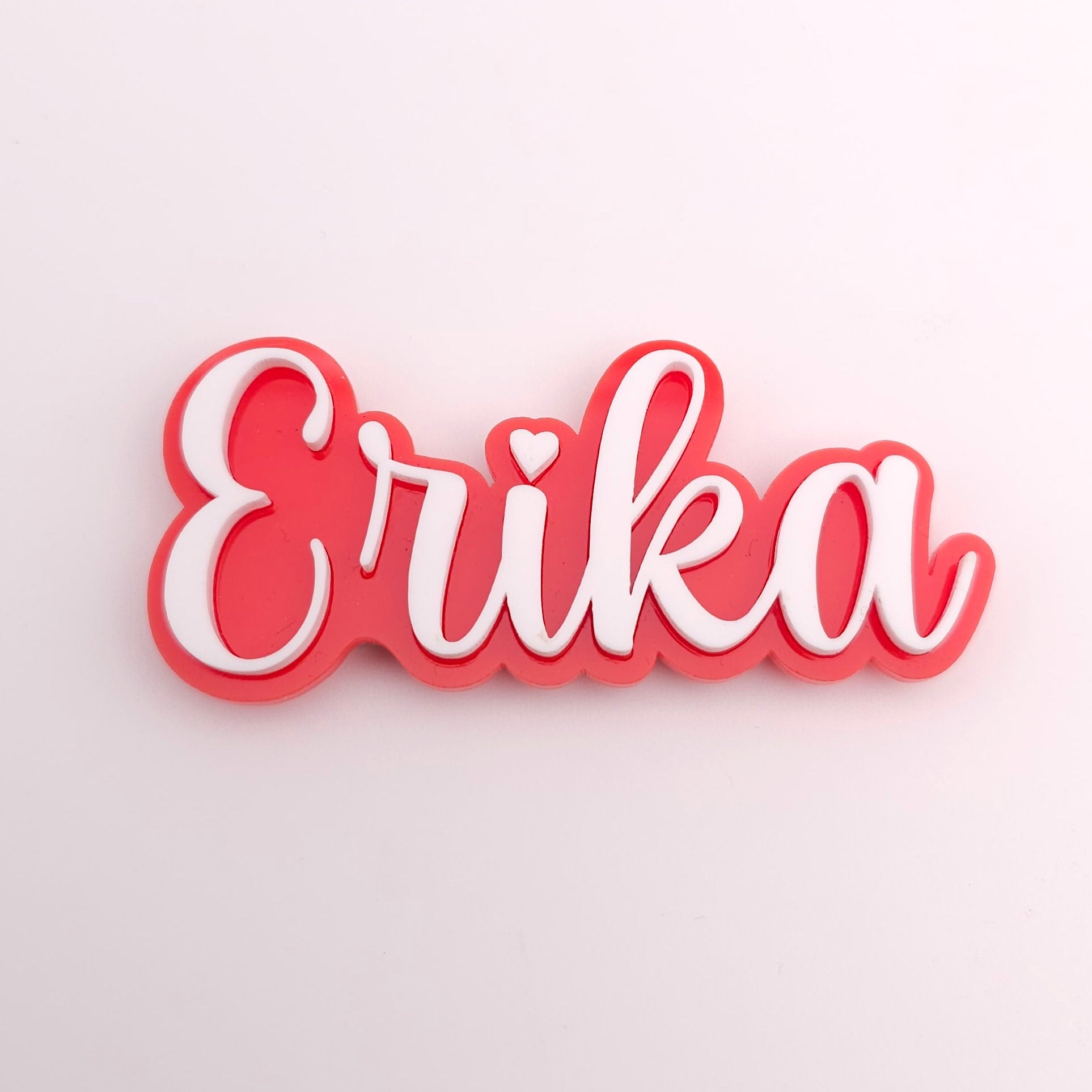 Red and white decorative nameplate with 'Erika' on a light gray background