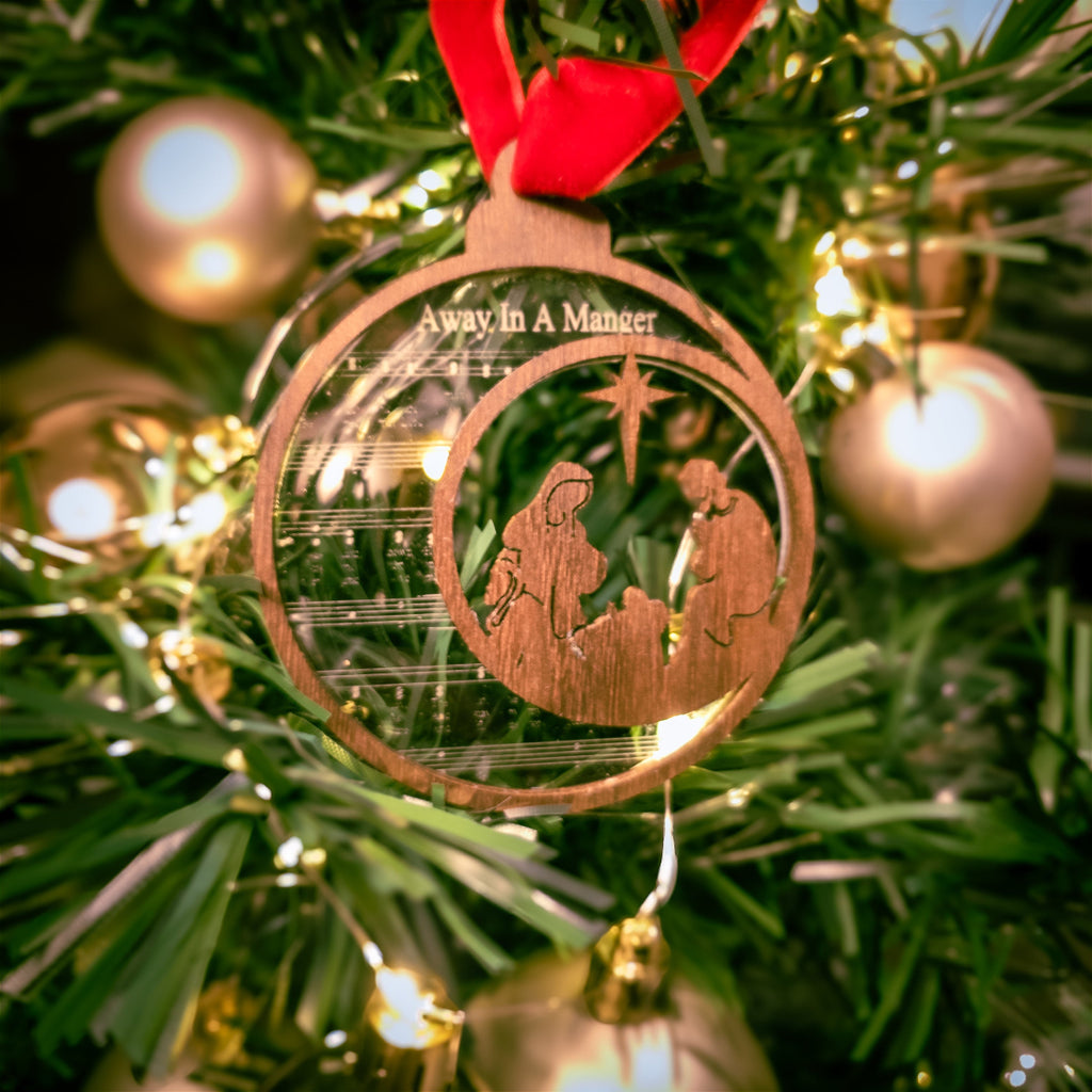 Wooden Christmas ornament with nativity scene on a decorated tree