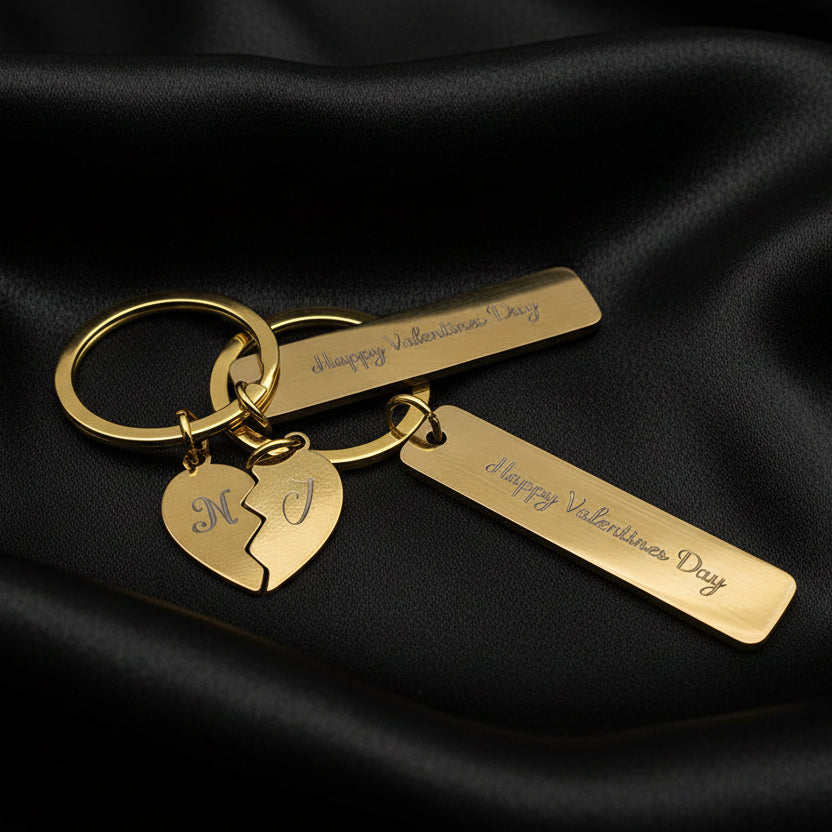 Gold keychain with engraved tags and a heart-shaped charm on a light gray background
