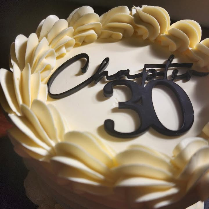 Cake with white frosting and 'Happy 30' decoration on a dark background