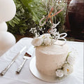Small white cake with floral decorations on a table with cutlery