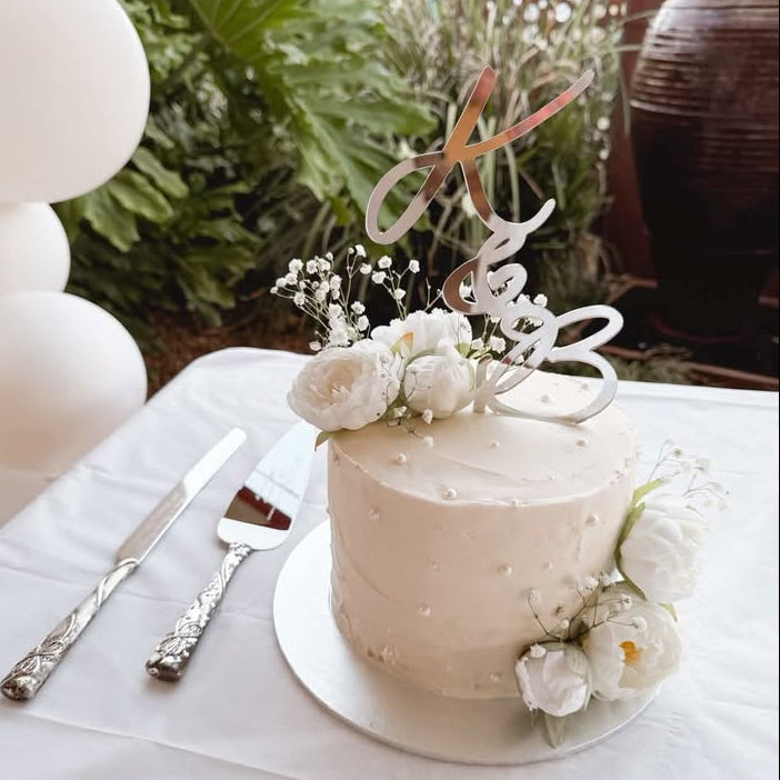 Small white cake with floral decorations on a table with cutlery