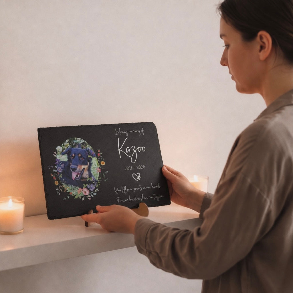 Person holding a black pet memorial book with a dog's portrait and text on a white surface.