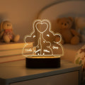 Neon light shaped like a family with four members and names on a dark background