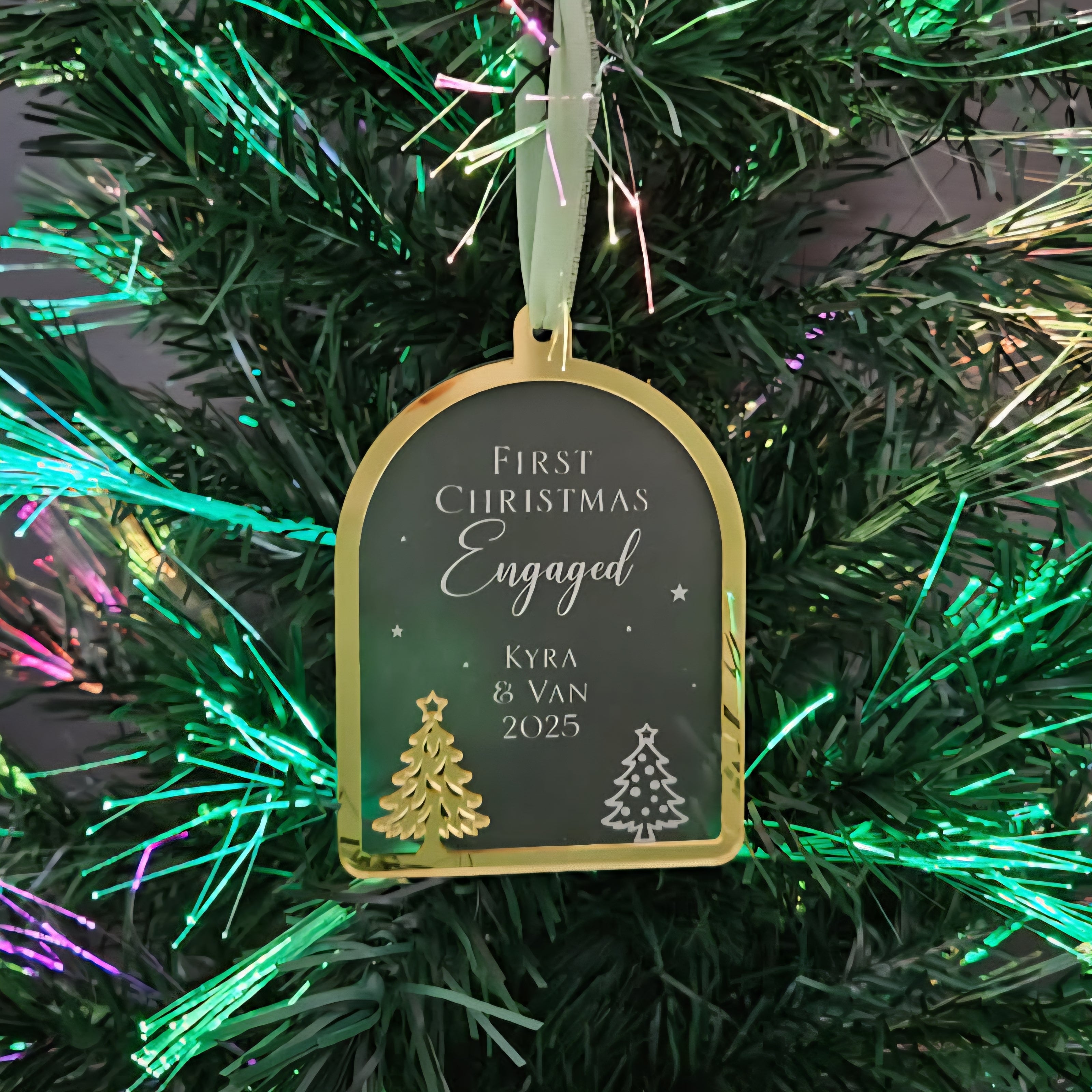 Decorative ornament tag on a Christmas tree with text 'First Christmas Engaged Kyra & Van 2025'.