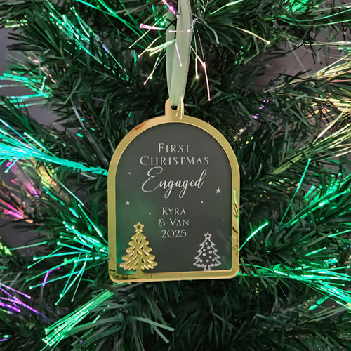 Decorative ornament tag on a Christmas tree with text 'First Christmas Engaged Kyra & Van 2025'.