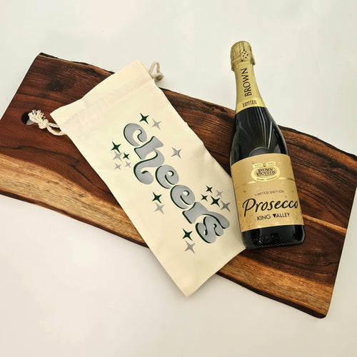 Bottle of Prosecco with a decorative bag on a wooden board