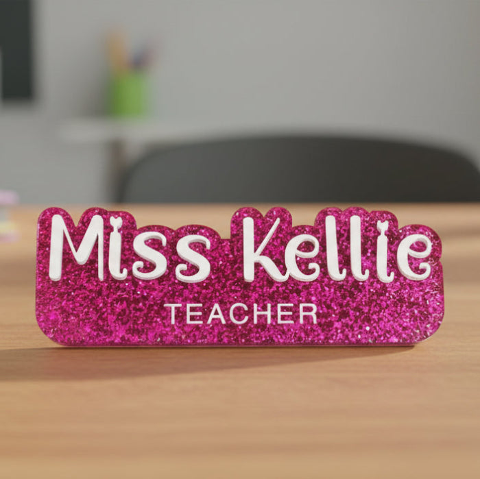 Pink glittery name tag with 'Miss Kellie Teacher' text on a white background