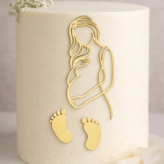 Gold mirror maternity and baby footprint acrylic fropper set displayed on a baby shower cake
