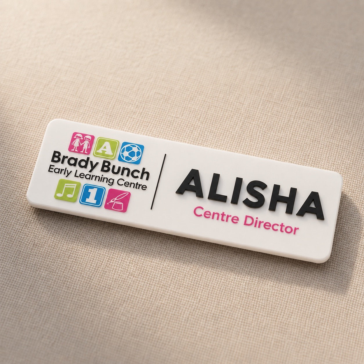 Angled product photo of custom early learning centre staff badge with raised black acrylic name lettering