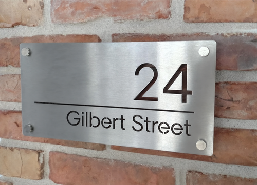 Custom brushed stainless steel house sign with laser-cut 24 Gilbert Street address mounted on brick wall
