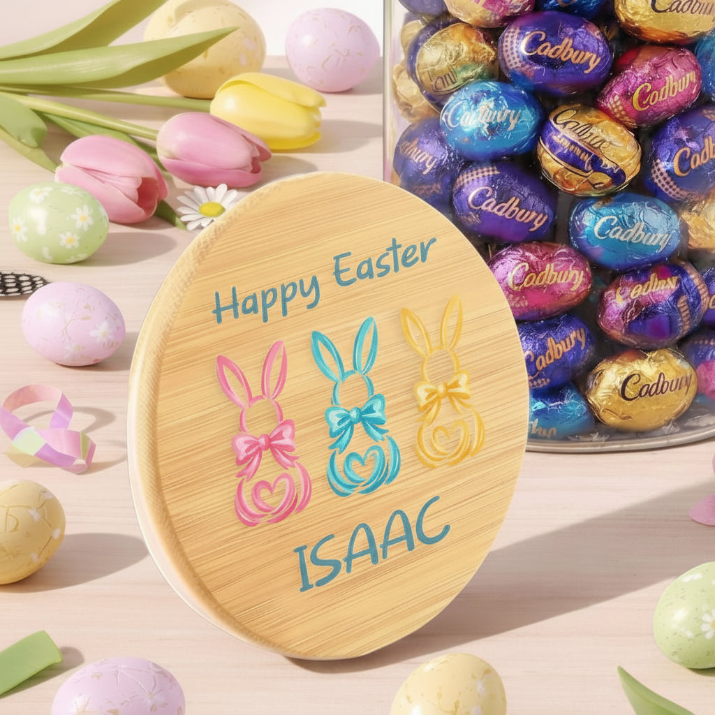 Personalized Easter plate with bunnies and 'Happy Easter Isaac' text, surrounded by Cadbury eggs and Easter decorations.