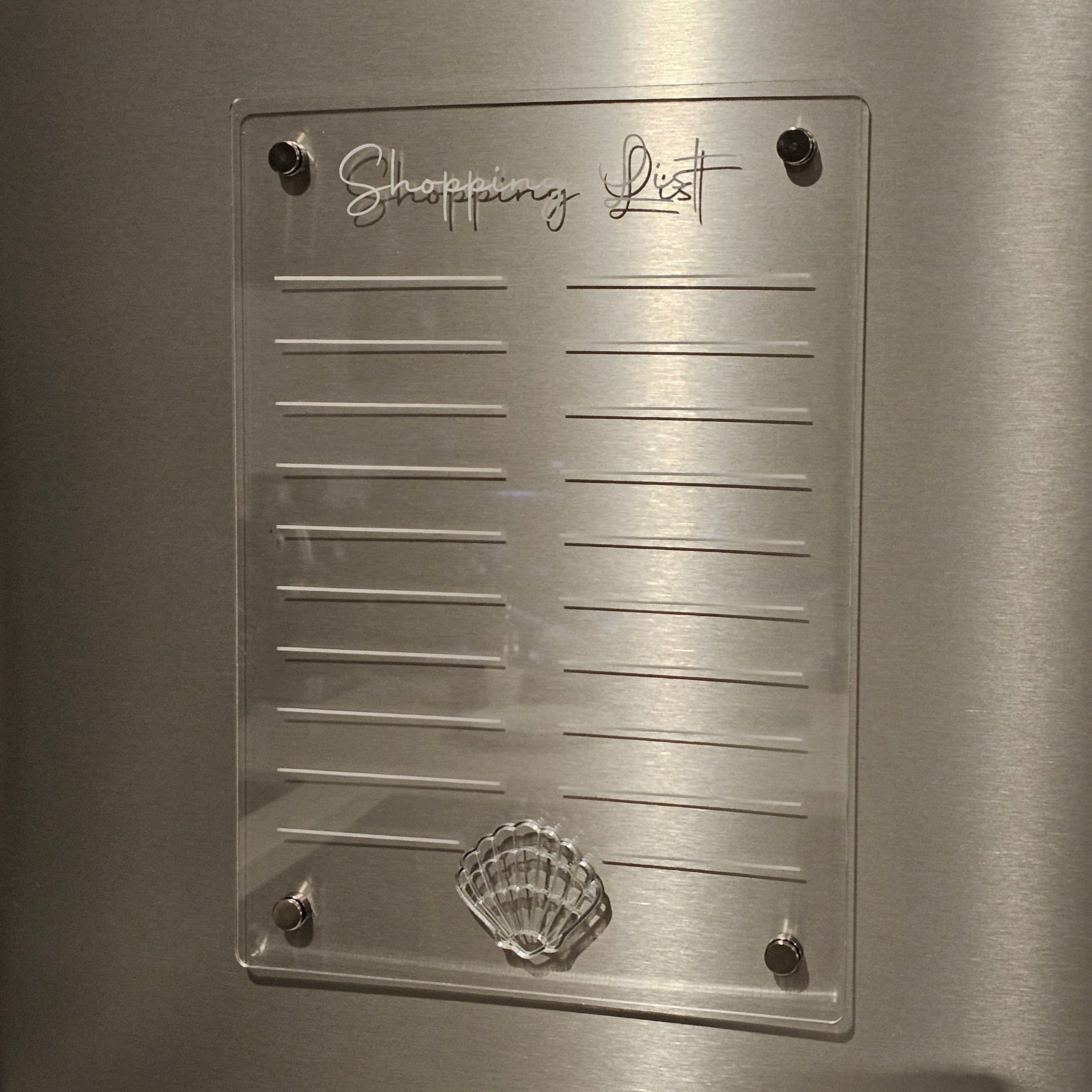 Clear acrylic shopping list with shell design on a metallic surface