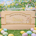 Wooden Easter basket with personalized name plaque in an outdoor setting with Easter eggs and bunnies.